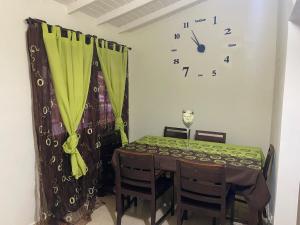 a dining room with a table and a clock on the wall at Sxm Paradise Town House in Marigot