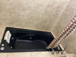 a black bathtub in a tile floor with a brown leash at Sxm Paradise Town House in Marigot