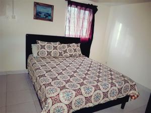 a bedroom with a bed with a comforter and a window at Sxm Paradise Town House in Marigot
