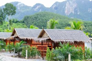 dom z dachem krytym strzechą przed górą w obiekcie Khaosok River Stone Resort & Camp w mieście Ban Thung Lang Tham +77 zdjęć