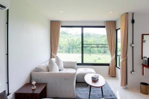 salon z kanapą i dużym oknem w obiekcie Khaosok River Stone Resort & Camp w mieście Ban Thung Lang Tham