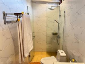 a bathroom with a toilet and a glass shower at Villa Mangga-Griya Taksu in Ubud