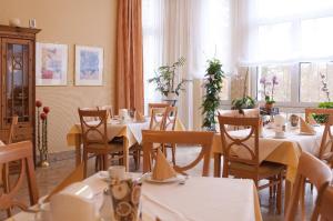 una sala da pranzo con tavoli e sedie bianchi e finestre di Hotel Haus am Park a Bad Homburg vor der Höhe