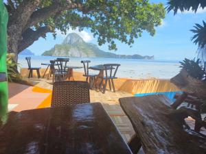 a table and chairs on a beach with a view of the ocean at Hadefe Cottages Beach Front in El Nido