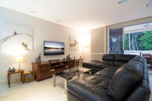 sala de estar con sofá de cuero y TV de pantalla plana en Whispering Palms - Beachfront Port Douglas, en Port Douglas
