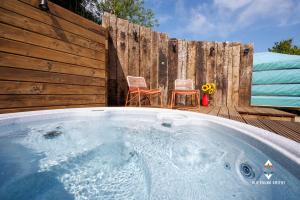 a hot tub with two chairs and a wooden fence at Old Pound Smithy in Bideford