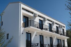 a white building with chairs on the balcony at GLP Sivota in Syvota