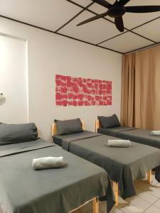 クチンにあるNatol Homestay - Venice 2 Samajaya Tabuan Tranquility Townshipのベッド3台と天井ファンが備わる客室です。