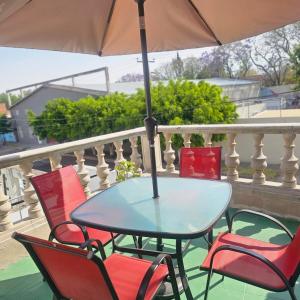 a table and chairs on a balcony with an umbrella at Casa Centurias céntrico con mini Split in Aguascalientes
