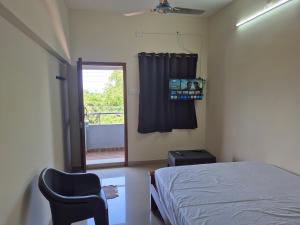 a bedroom with a bed and a chair and a window at STM StayInn in Nāttarasankottai