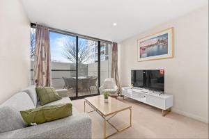 a living room with a couch and a tv at Spacious 3-Bedroom Apartment + Lifestyle Amenities in Downer