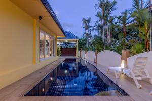 a swimming pool with white chairs next to a house at V245 3BR with Pool Close to Phuket Best Beaches in Rawai Beach