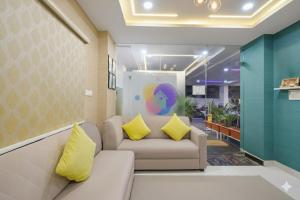 a living room with a couch and yellow pillows at Hotel Urban Stayz, HITEC City, Hyderabad in Hyderabad