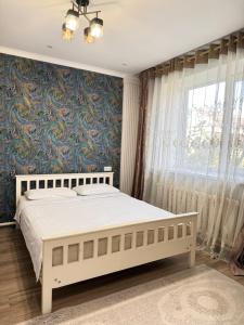 a bedroom with a white bed and a blue wall at Apart Le Mont in Karakol