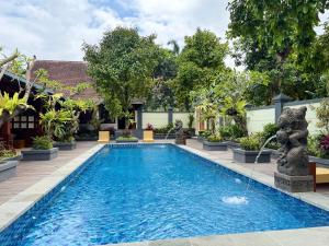 a swimming pool in front of a house with trees at Villa Mangga-Griya Taksu in Ubud +8 photos