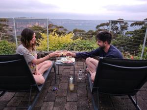 a man and a woman sitting at a table with wine glasses at Garden of the Stars - Studio - Breathtaking View, Echo Point in Katoomba