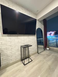 Una habitación con un televisor de pantalla plana grande en una pared de ladrillos. en Acogedor Loft con ubicación céntrica en Lima, en San Antonio