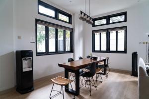 une salle à manger avec une table, des chaises et des fenêtres dans l'établissement Casuarina Villa - City Center American Classic Villa, à Bandung 15 autres photos