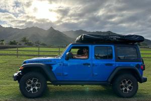 a blue jeep with a person sitting in the back at Island Getaway Camper Cozy Rooftop Tent & Full Gear Kauai in Anahola