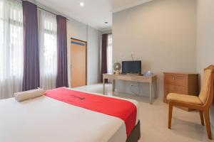 a bedroom with a bed and a chair and a television at RedDoorz at Palagan Joglo Sersan Bajuri in Bandung