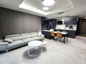 a living room with a couch and tables and a kitchen at SoYou osiria residence in Busan