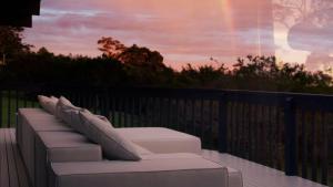 a row of white pillows on a balcony with a sunset at Escape to Summer, Bilgola Plateau IH Luxe in Bilgola