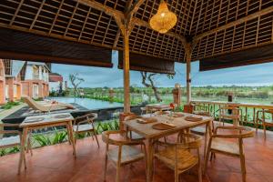 a dining room with tables and chairs and a pool at Dewi Sri Villa in Ubud