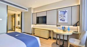 a bedroom with a bed and a table and a tv at Echarm Hotel Changchun Yiqi Automotive Trade City Wanda in Changchun