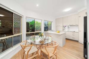 a kitchen and dining room with a glass table and chairs at Sea La Vie - Walk to beach & CBD in Maroochydore +24 photos