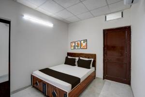 a bedroom with a bed with white walls and a door at HOTEL O ROYAL INN in Indore +24 photos