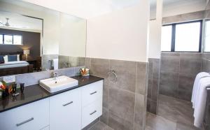 a bathroom with a sink and a mirror at Cowrie Beach House Port Douglas in Port Douglas