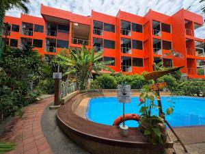 an orange building with a swimming pool in front of a building at LAY TONG BEACH HOTEL Patong in Patong Beach