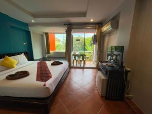 a bedroom with a bed and a television and a balcony at LAY TONG BEACH HOTEL Patong in Patong Beach