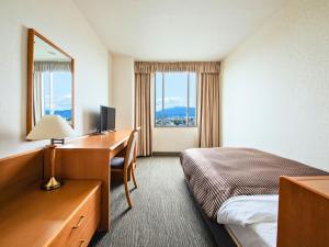a hotel room with a bed and a desk with a computer at Hotel Concorde Hamamatsu in Hamamatsu