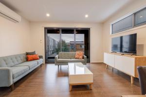 a living room with a couch and a table at Stylish 3-Bedroom Townhouse Near Shops & Parks in Point Cook