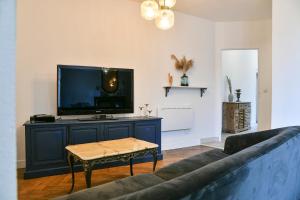 Charmant T4 Centre-ville, Lacs et Montagnes في Le Pont-de-Beauvoisin: غرفة معيشة مع أريكة وتلفزيون بشاشة مسطحة