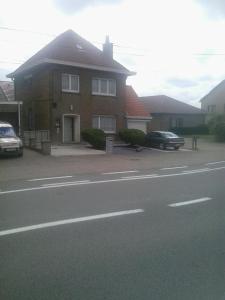 a house with two cars parked in front of it at Guesthouse SiSa in Veurne