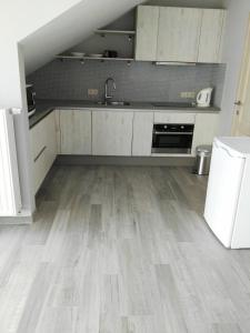 a kitchen with white cabinets and a wooden floor at Guesthouse SiSa in Veurne