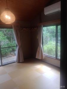 ein leeres Zimmer mit zwei Fenstern mit Vorhängen in der Unterkunft ファミーユグループ城ケ崎店 空音sorane in Ito