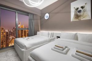 two beds in a room with a view of a city at Restay Homes at Act Towers - Pool access with Burj View in Dubai +140 photos