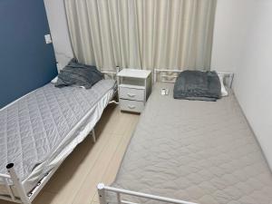 two twin beds in a room with a night stand at 嘉翔の家 in Otsu