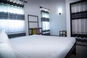 a large white bed in a room with windows at White Villa Kosgoda in Kosgoda