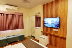 a hospital room with a flat screen tv on a wall at Hotel Asilo Prime in Indore