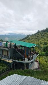 a building with a green roof on a hill at Bloom's Nest Kasar devi in Hawālbāgh