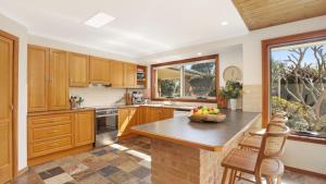 a kitchen with wooden cabinets and a bowl of fruit on a counter at Coolburra in Culburra Beach