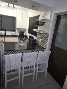 cocina con sillas blancas y encimera negra en Coastal Cove Langebaan, en Langebaan 2 fotos más