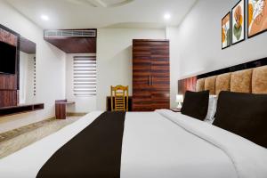 a bedroom with a large bed and a wooden door at Super Townhouse Bela Road Varanasi City Railway Station Formerly Srijan Grand in Varanasi +24 photos