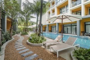 a resort pool with two lounge chairs and an umbrella at Pool View Condo 2204 Wyndham Garden Resort in Nai Thon Beach