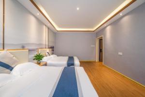 a hotel room with two beds and a hallway at Floral Hotel Guilin Banxing Garden in Guilin