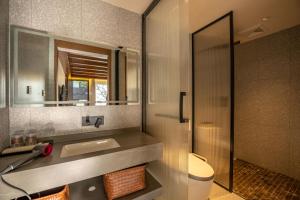 ein Badezimmer mit Waschbecken, Toilette und Spiegel in der Unterkunft Lijiang Jingshanyuan Meisu in Lijiang + 60 Fotos